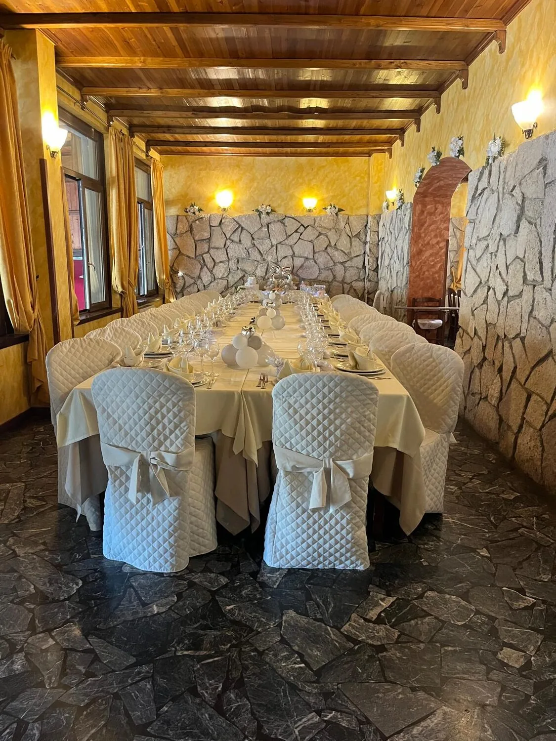 Sala interna con parete in pietra e soffitto in legno, tavolo imperiale apparecchiato — Le Colombe Da Tiziano